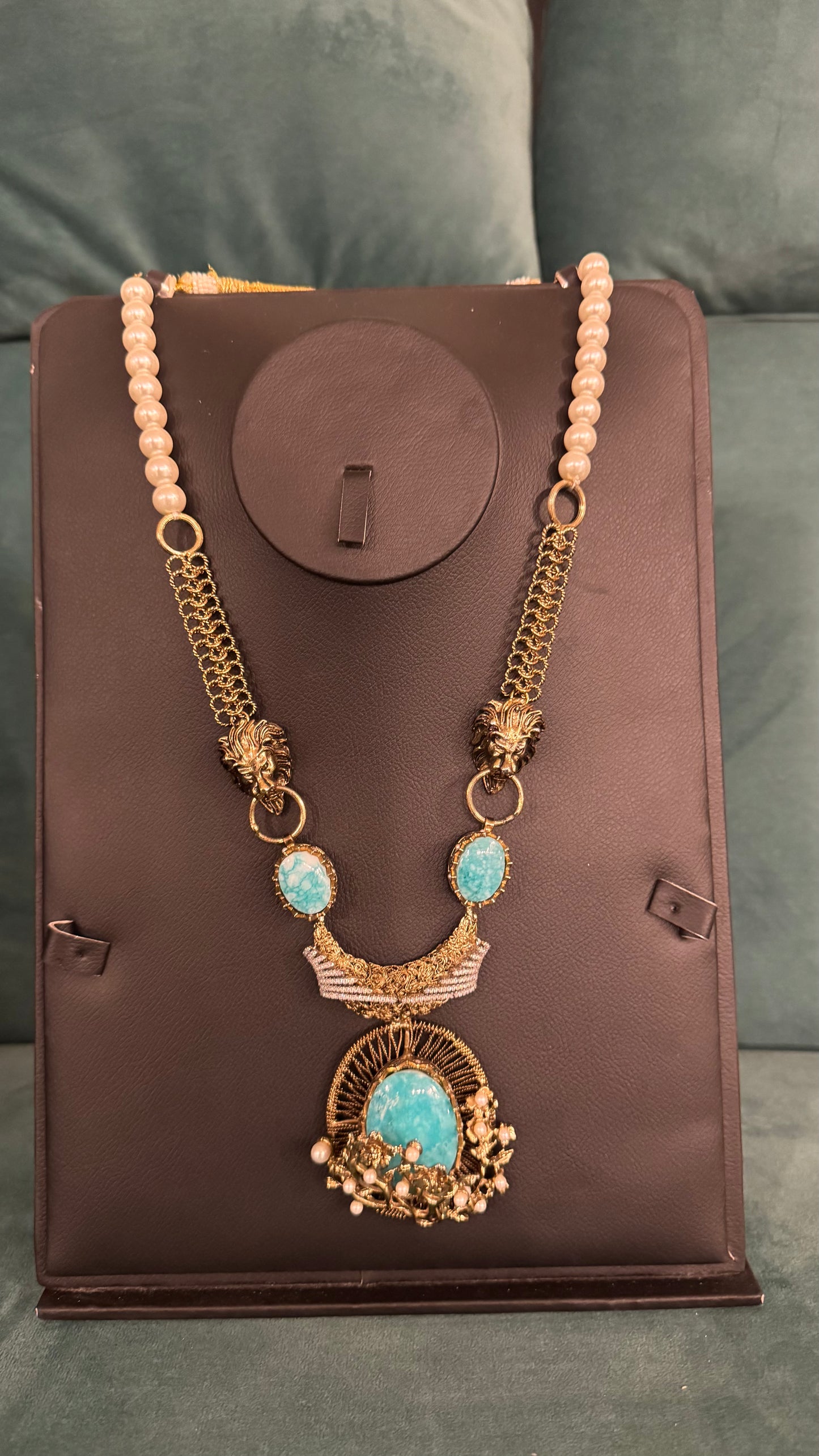 Gold pearl and turquoise necklace sets with crescent pendant and beaded chain on black jewelry stand