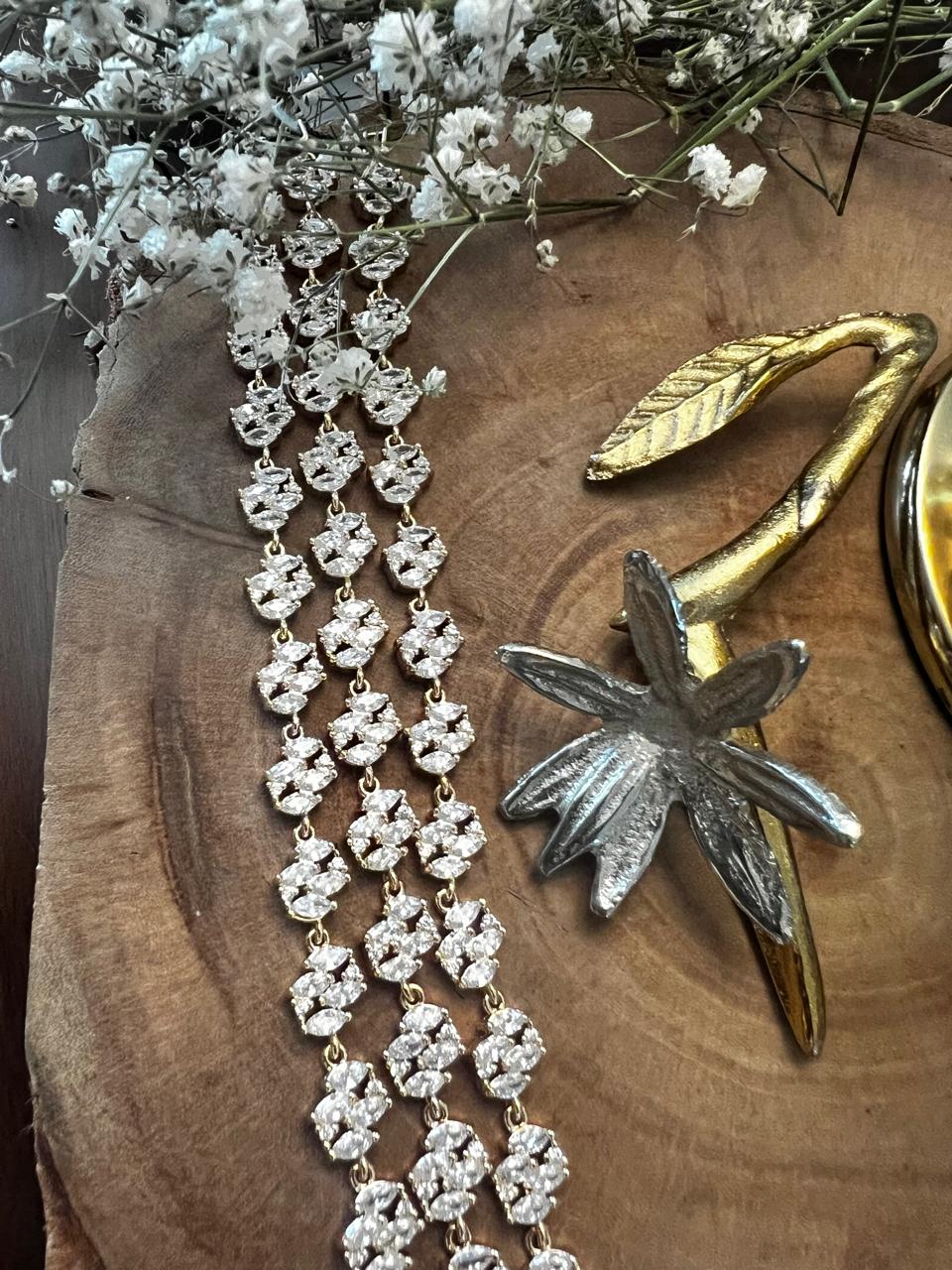 Floral chain jewellery with gold and silver flower sculpture on wood