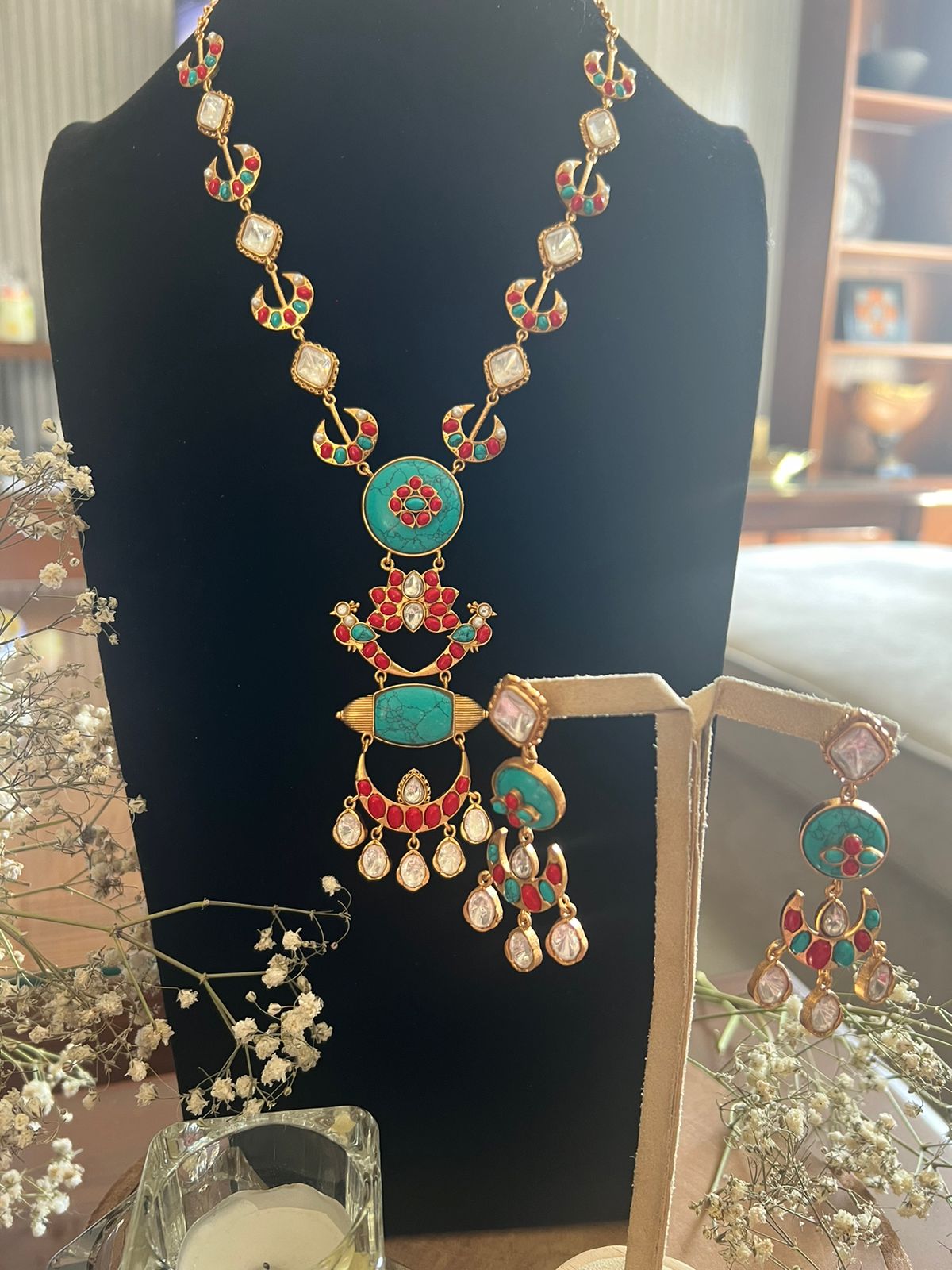Multicolour traditional necklace set with matching earrings displayed on a stand.