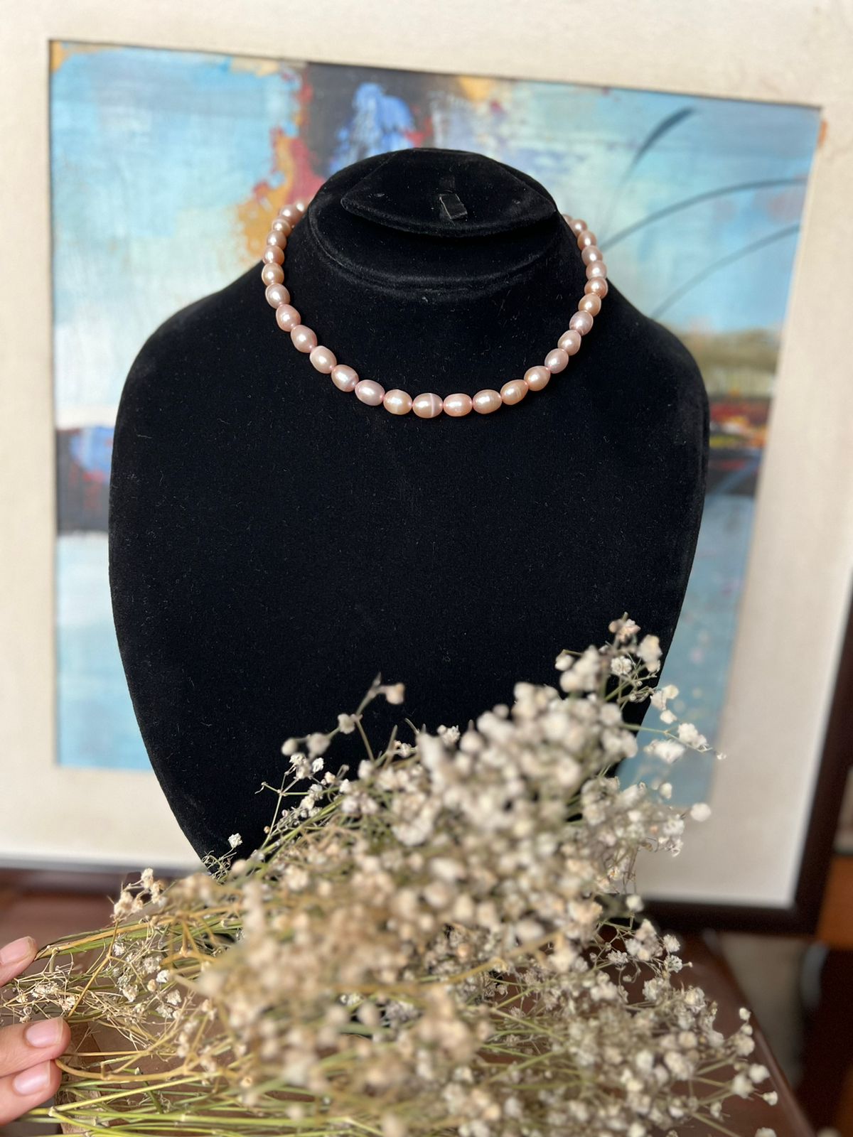 Classic pearl necklace displayed on a black jewellery stand.