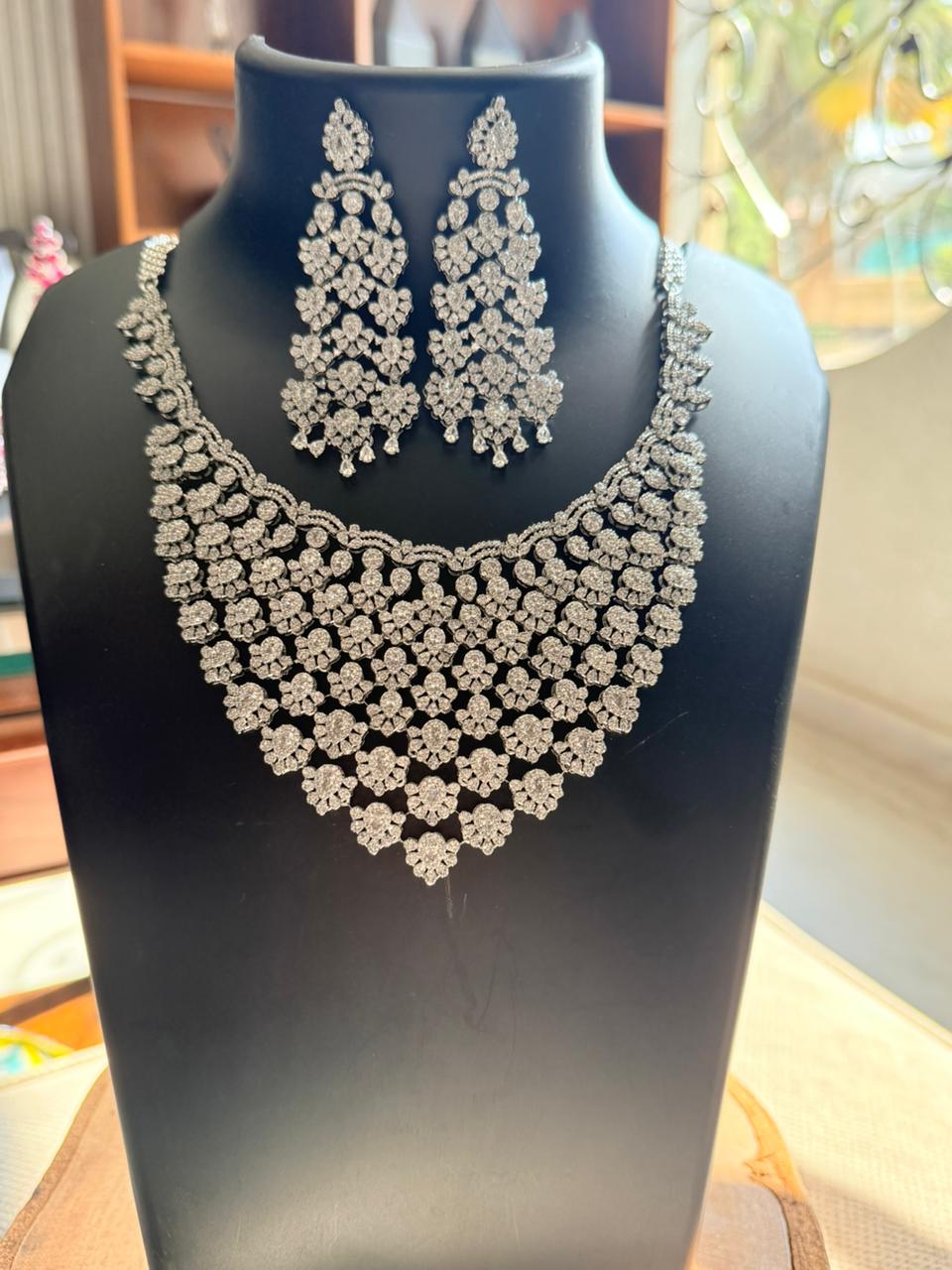 Silver necklace and earrings set on a black mannequin