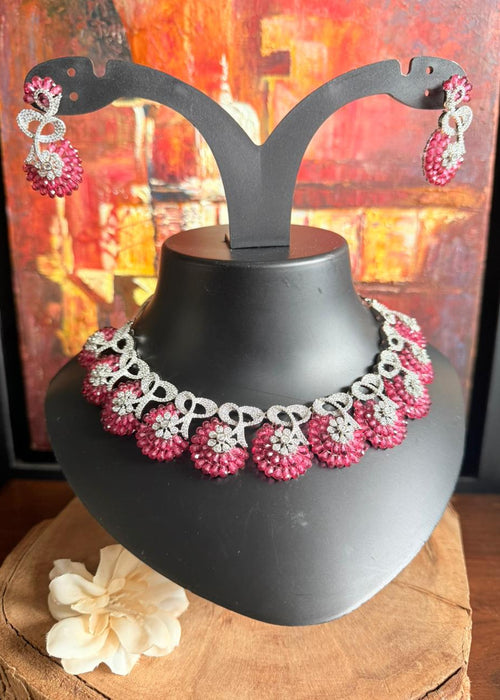 Necklace and earrings on a black stand with a colorful abstract background