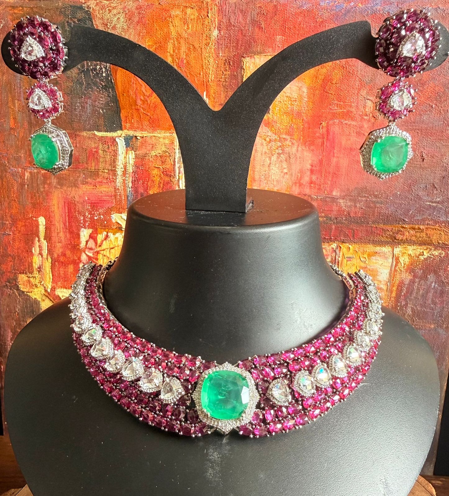 Jewelry set with necklace and earrings on a black stand against an abstract multicolored background