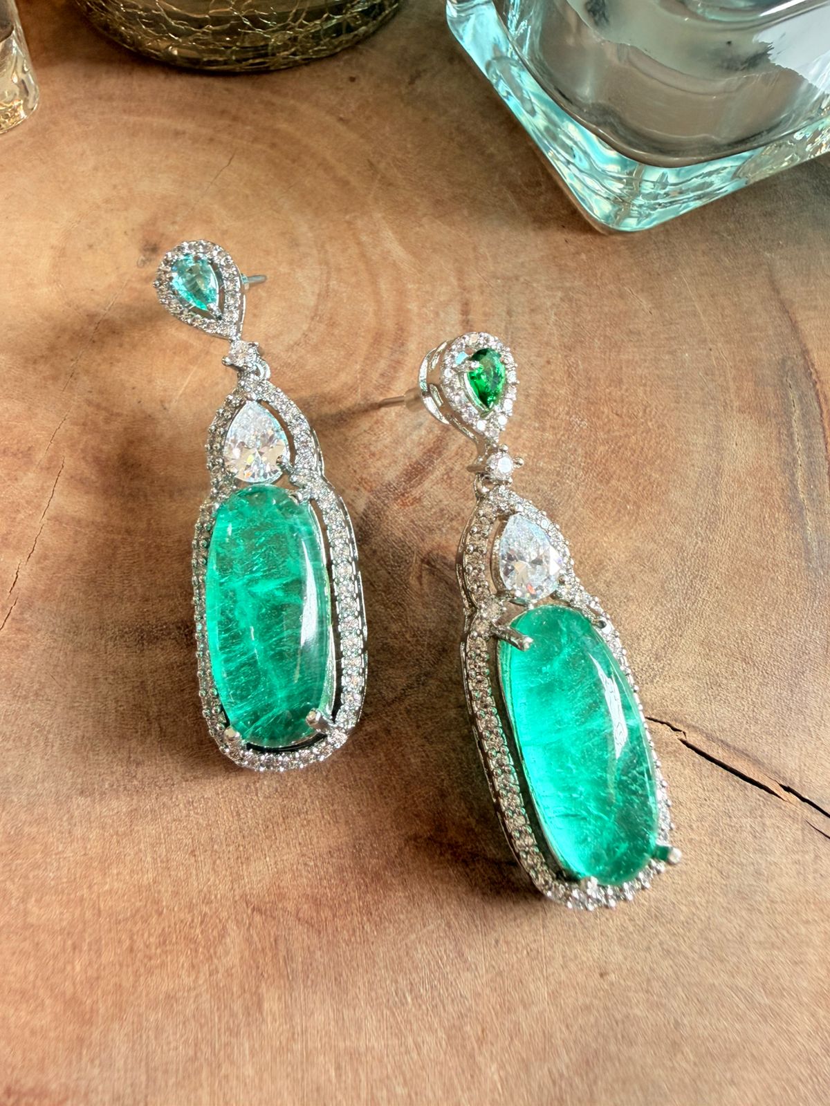 Pair of emerald earrings on a wooden surface