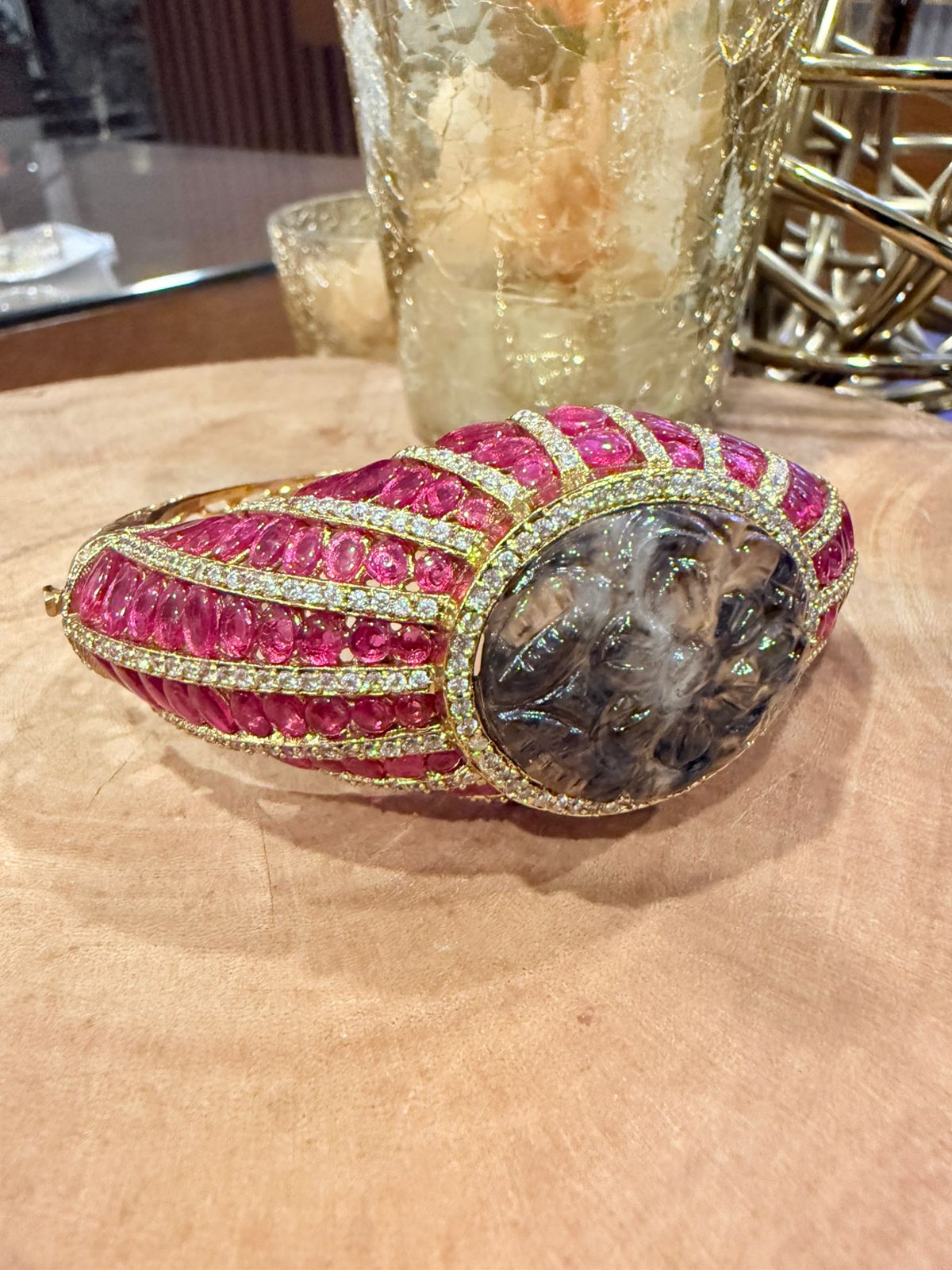 Decorative item with pink gemstones and gold accents on a beige surface
