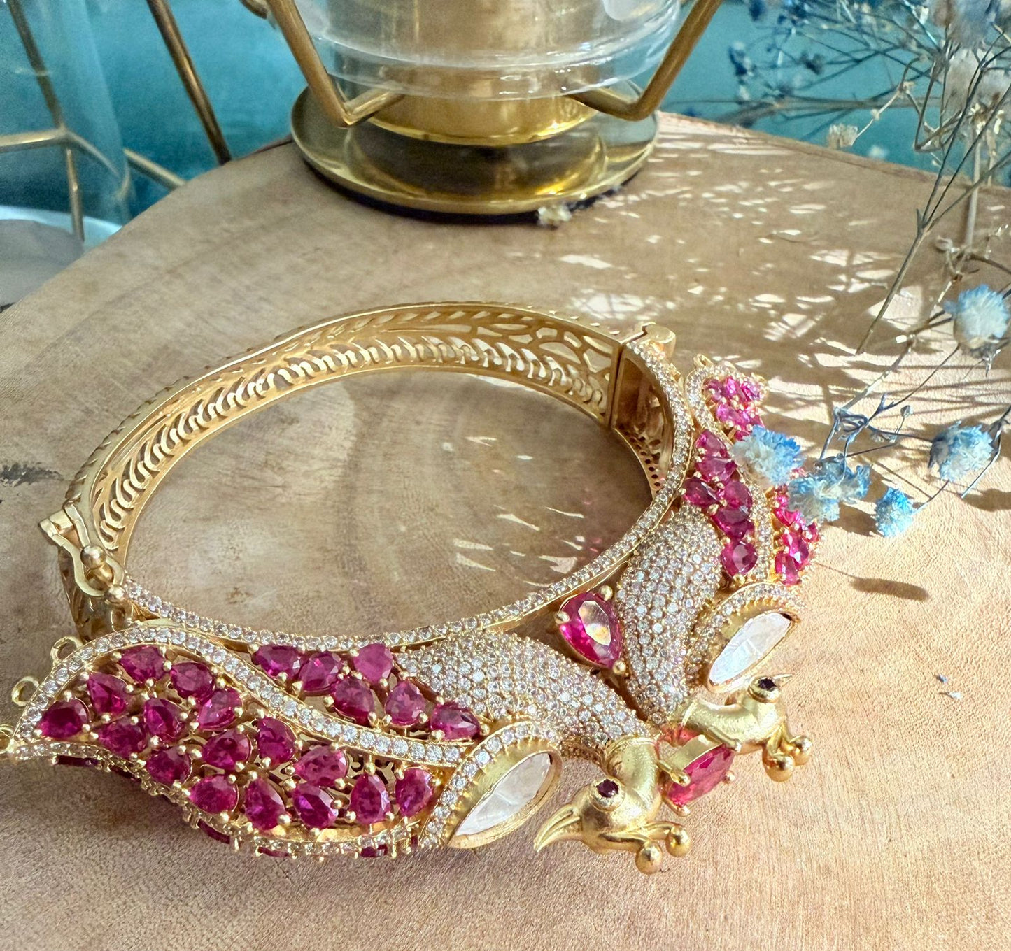 Gold bracelet with pink gemstones on a wooden surface