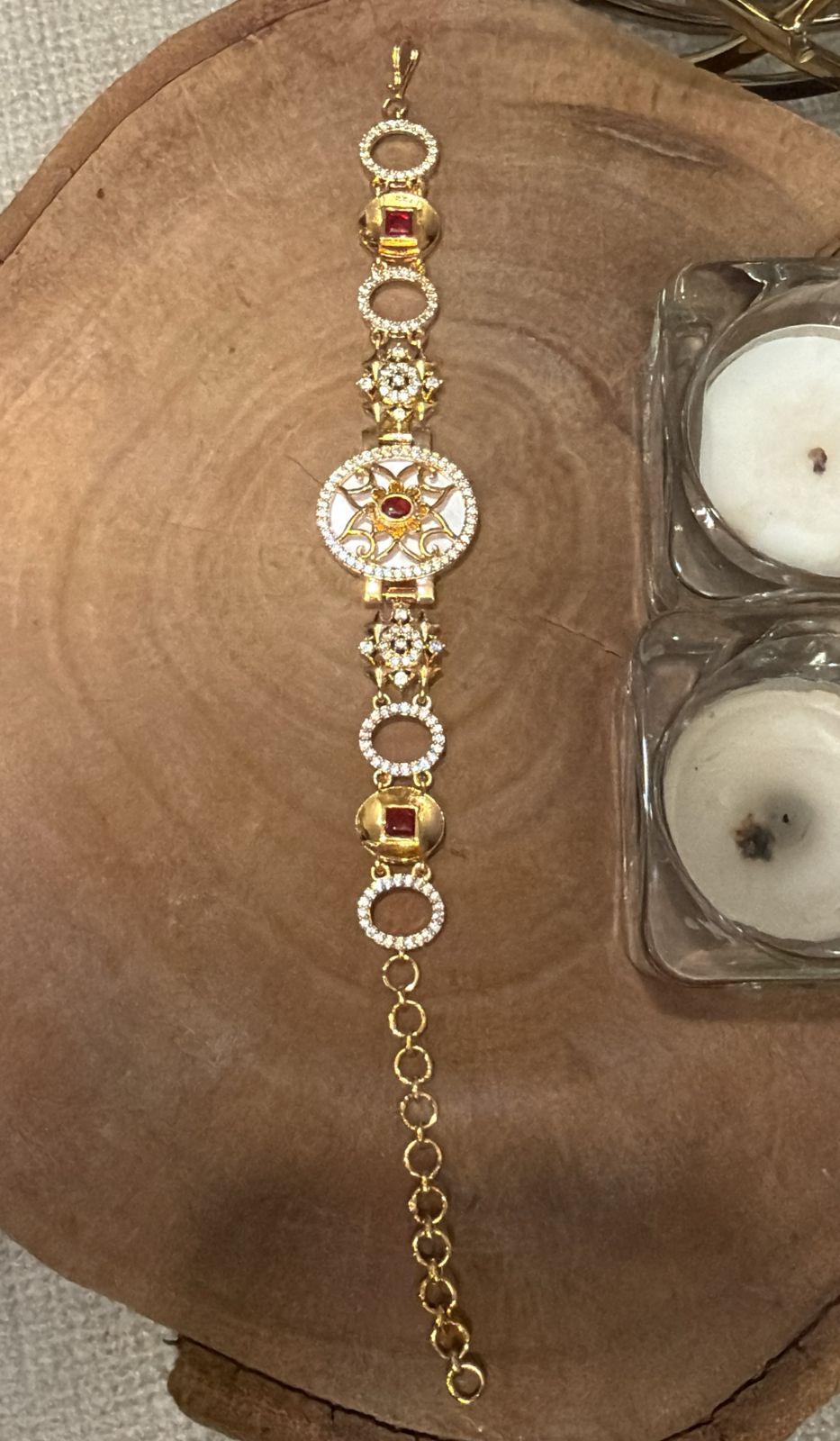 Gold bracelet with red gemstones on a wooden surface