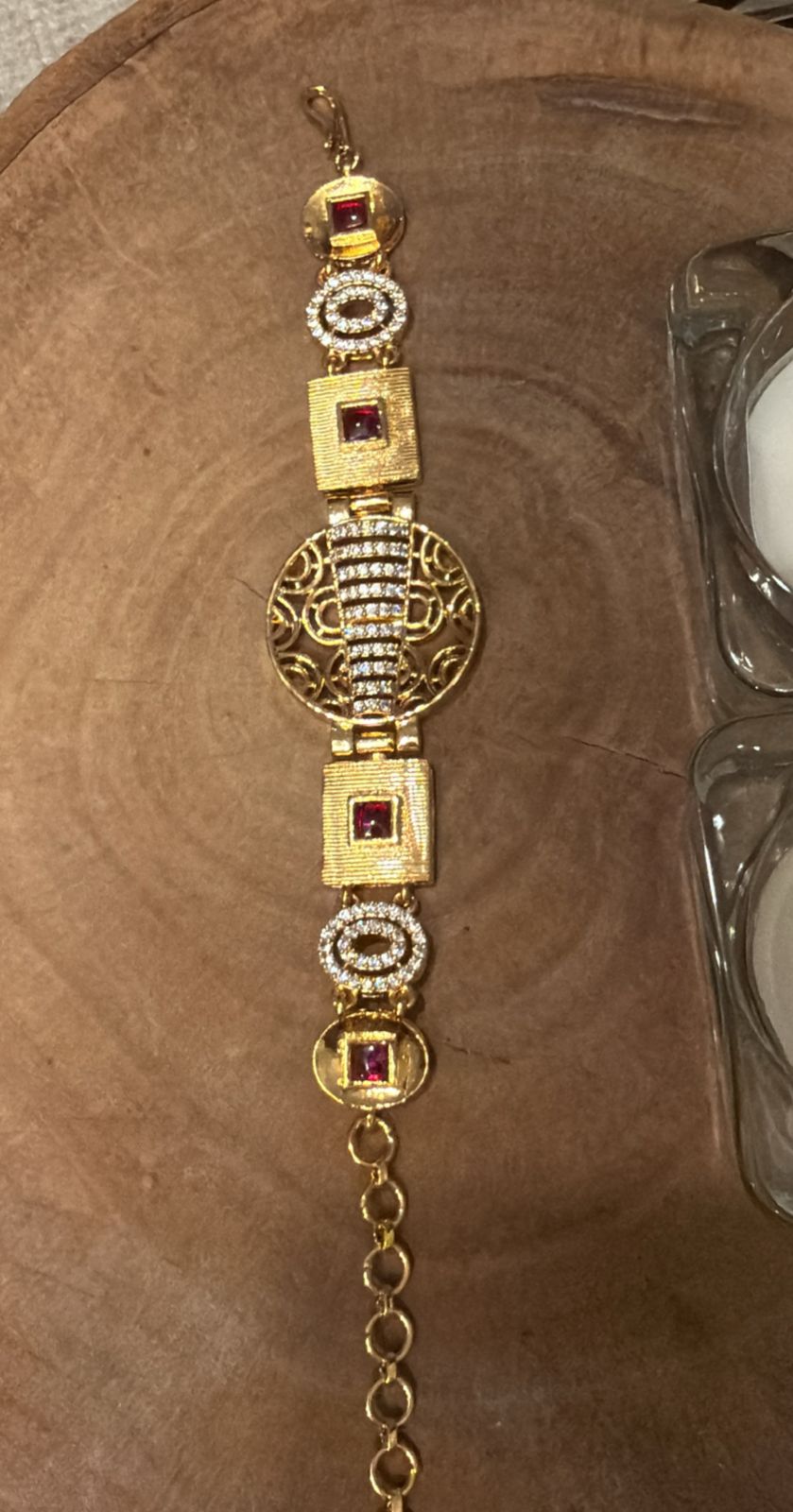 Gold bracelet with gemstones on a wooden surface