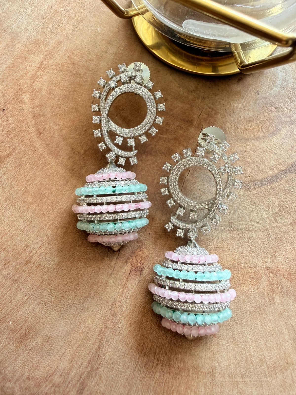 Pair of decorative earrings with pastel colors on a wooden surface
