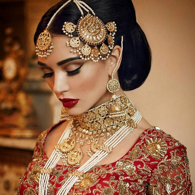 Pakistani bride in traditional red attire with elaborate gold jewellery