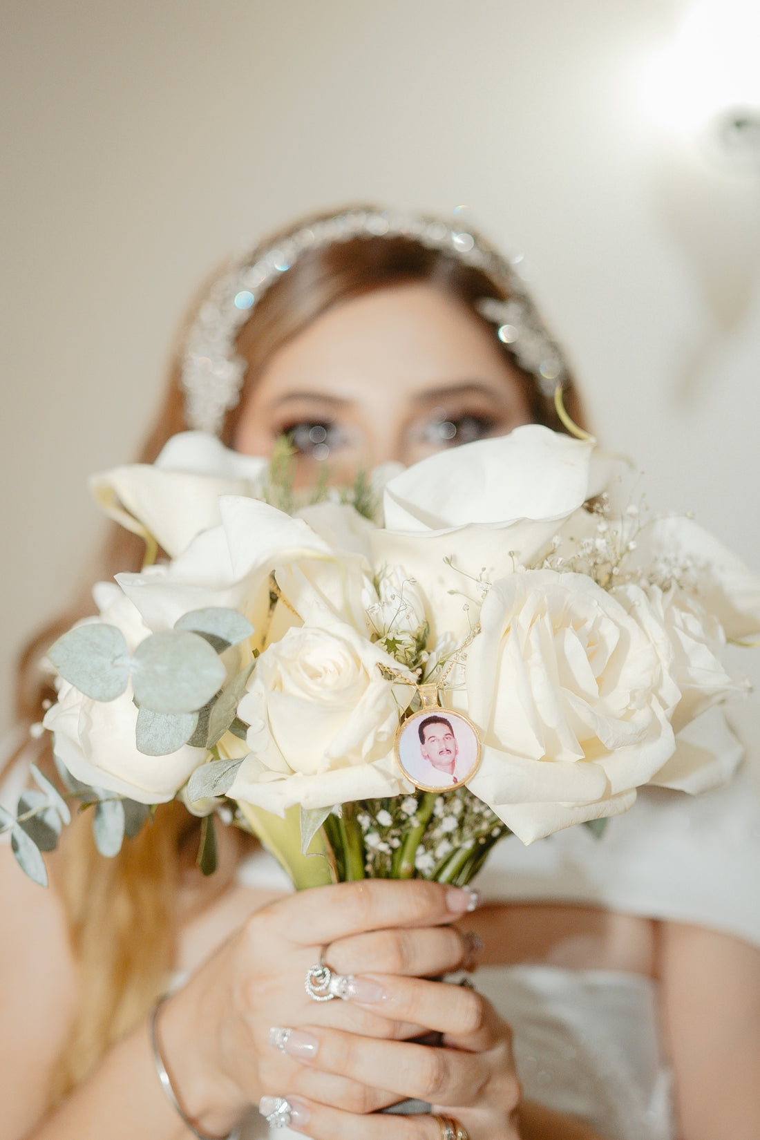 Bride holding white roses with a photo charm