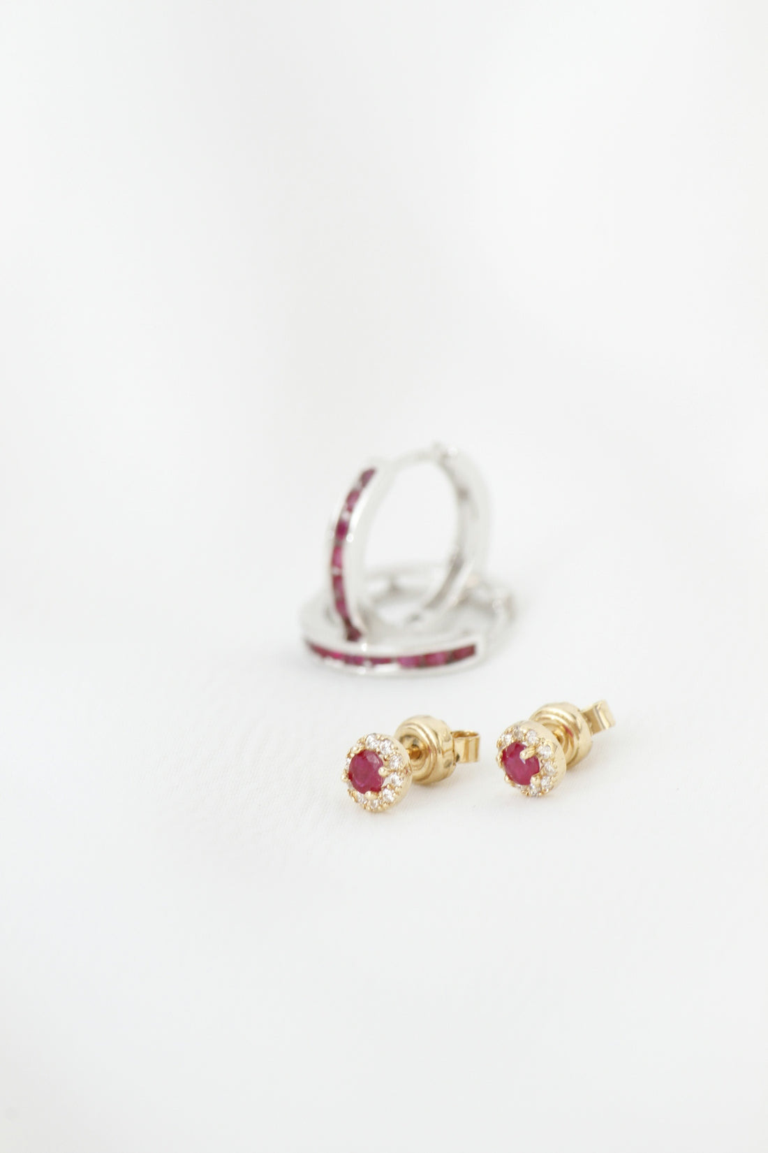 Two pairs of ruby and diamond earrings on white background