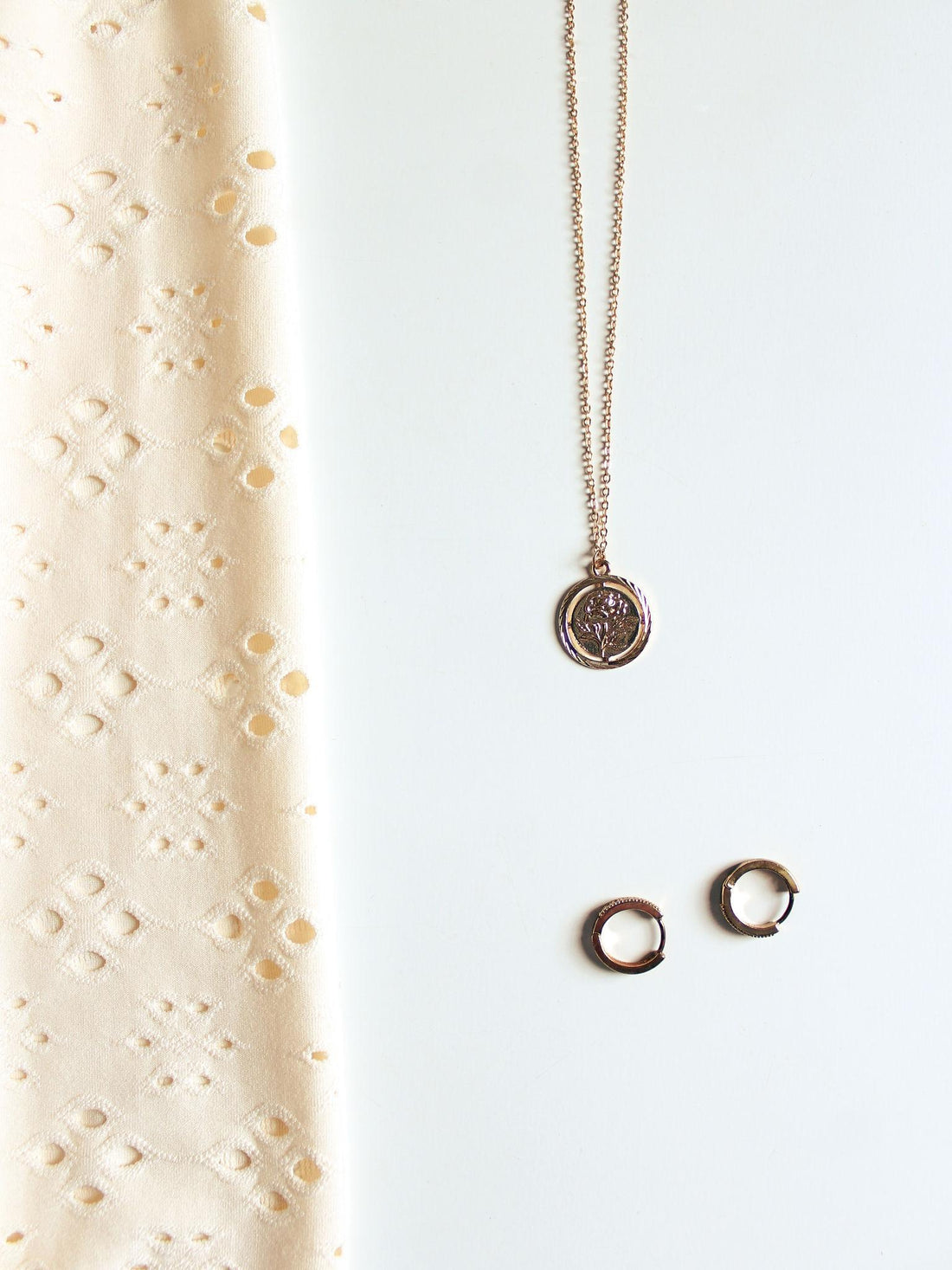 Modern gold and gemstone jewellery styled on neutral silk fabric