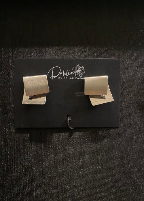 Matte gold geometric stud earrings displayed on a black Dahlia by Sehar Zafar card.