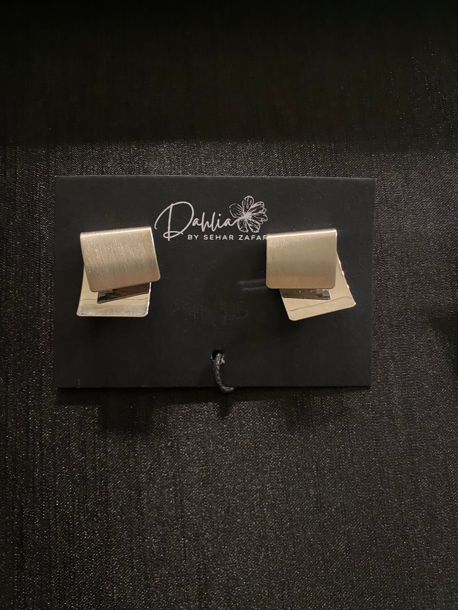 Matte gold geometric stud earrings displayed on a black Dahlia by Sehar Zafar card.