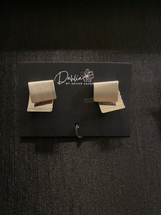 Matte gold geometric stud earrings displayed on a black Dahlia by Sehar Zafar card.