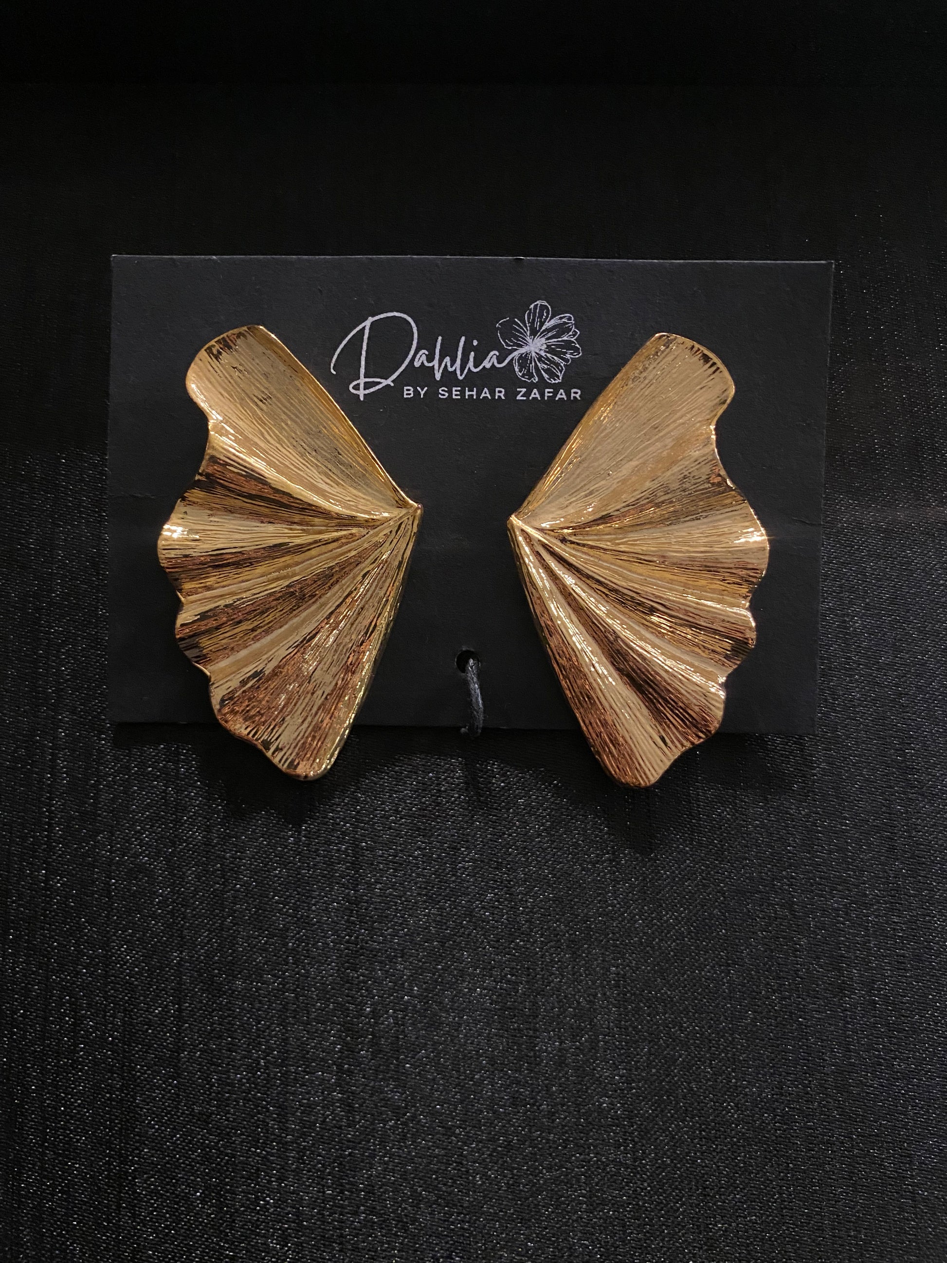 Gold textured fan shaped statement earrings displayed on Dahlia by Sehar Zafar card