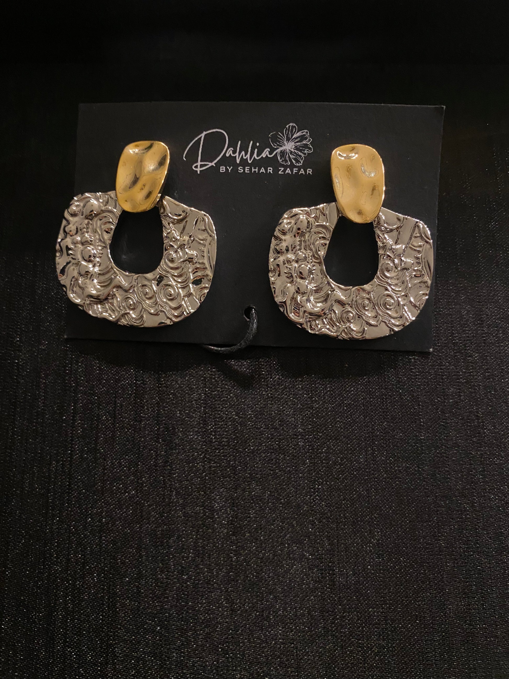Gold and silver textured statement hoop earrings on black display card