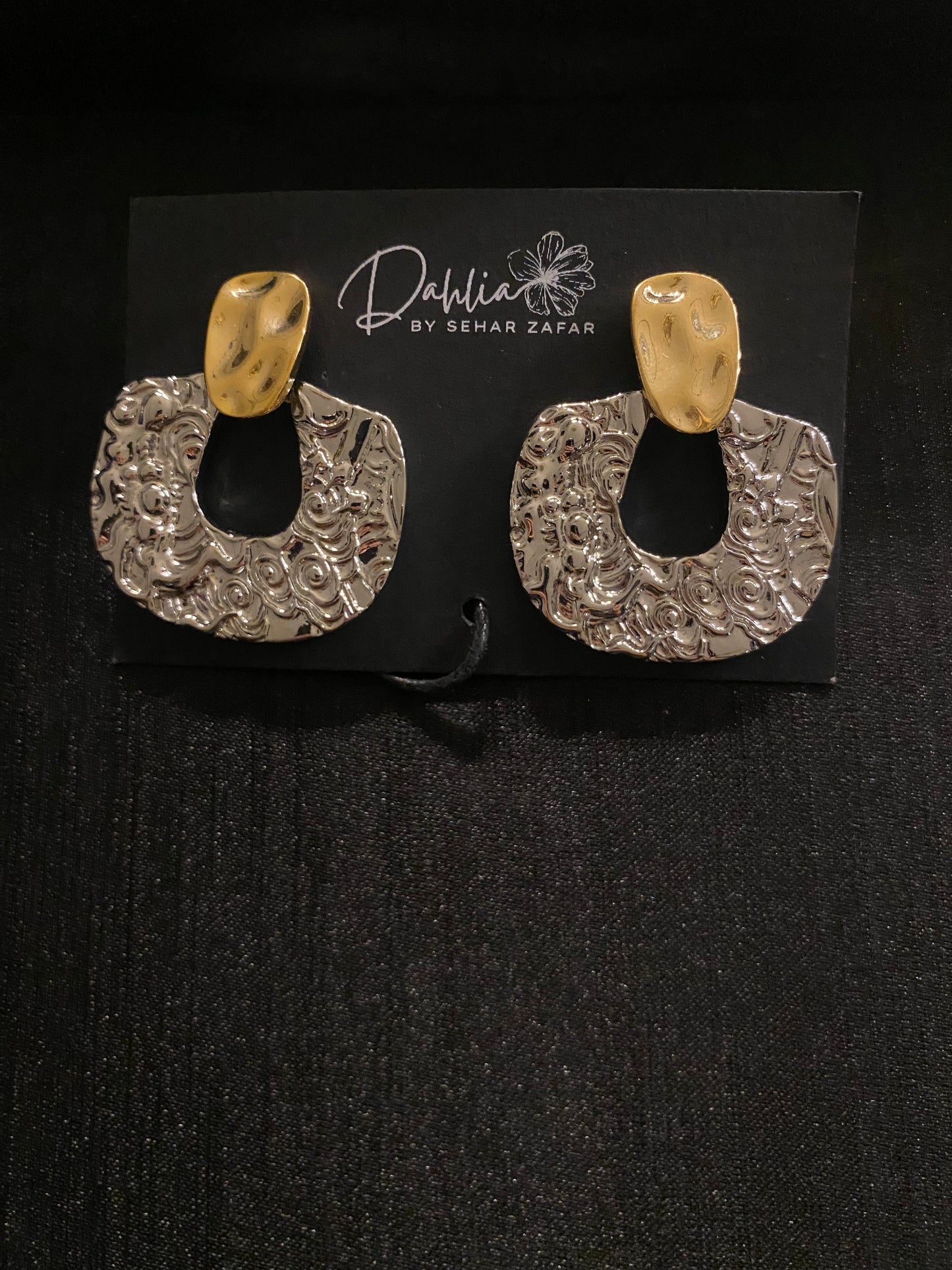 Gold and silver textured statement hoop earrings on black jewelry card