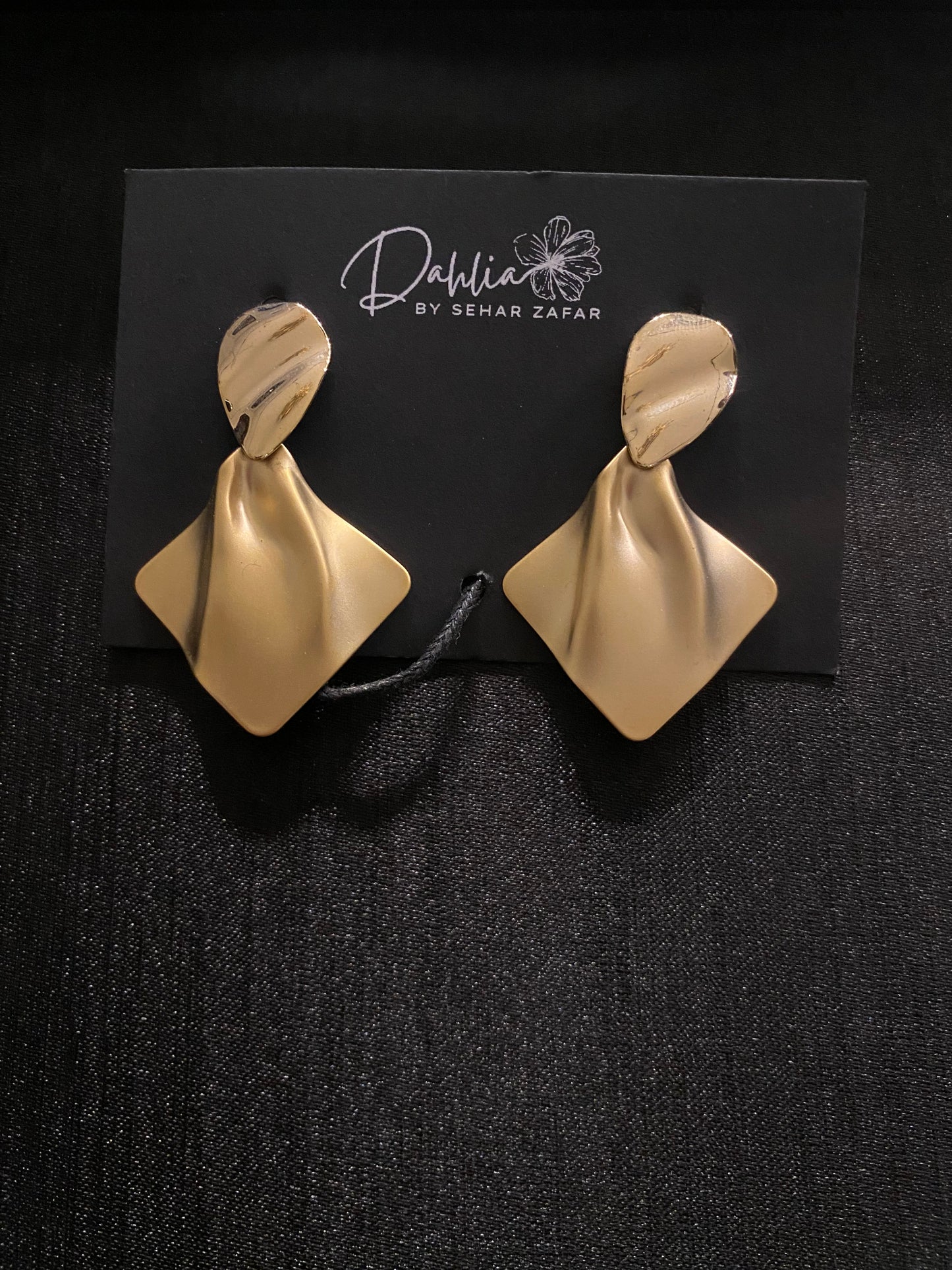 Gold folded earrings with marbled oval tops on black branded card