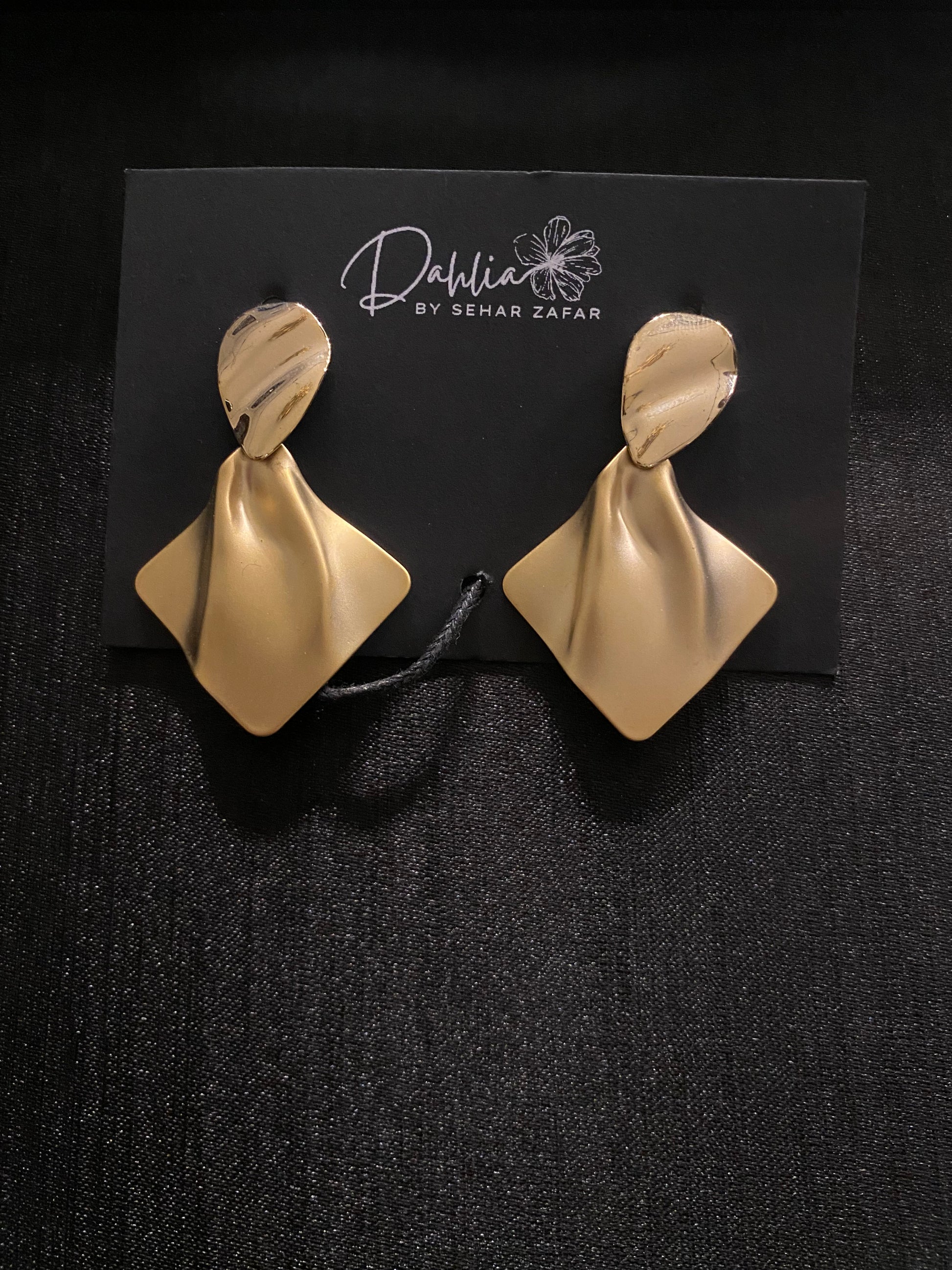 Gold folded earrings with marbled oval tops on black branded card