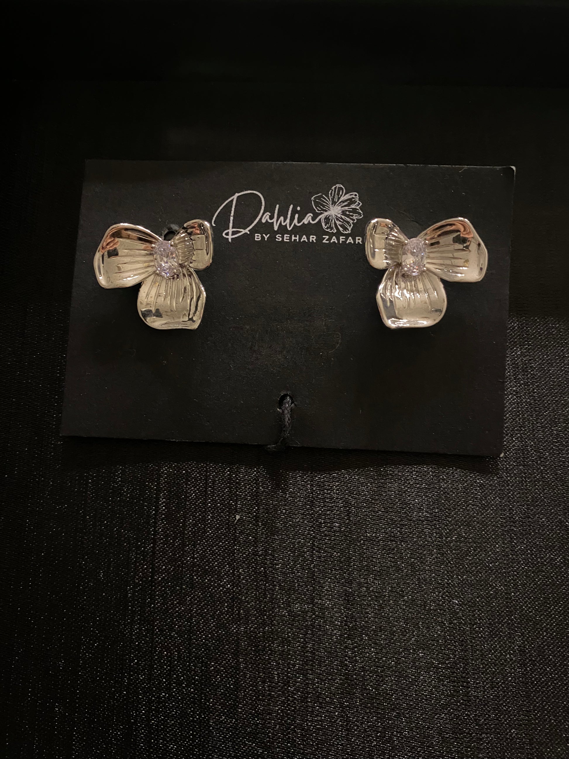 Translucent floral earrings with central gem on black branded card