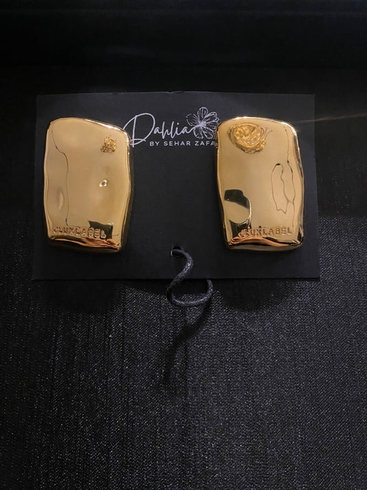 Glossy gold abstract rectangular earrings with engraved detail on black branded card