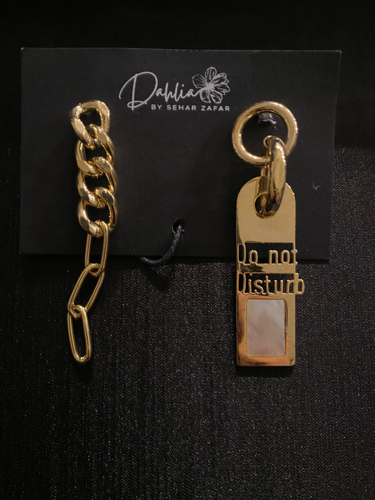 Gold chain link earring and engraved pearl tag earring on black branded card