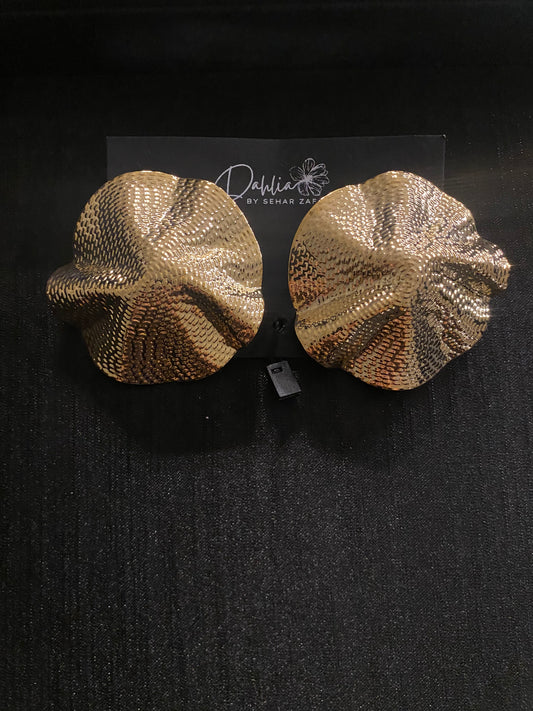 Gold abstract earrings with wavy floral-shell texture on black branded card