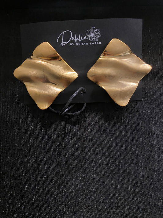 Gold abstract square earrings with wavy texture on black branded card