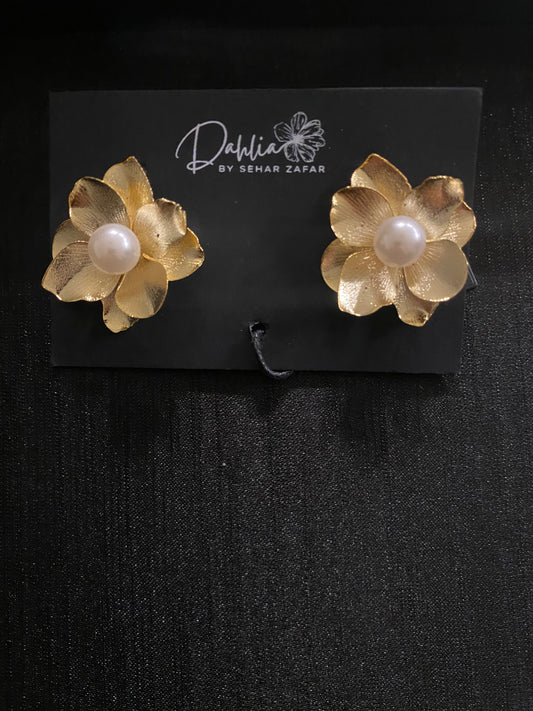 Gold flower earrings with pearl center on black branded card