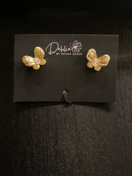 Gold butterfly earrings with textured wings and gemstone center on black branded card