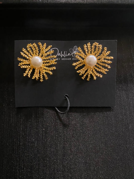Gold sunburst earrings with pearl center and textured branches on black branded card