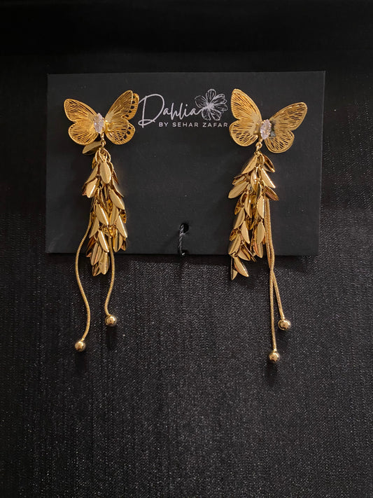 Gold butterfly earrings with gemstone center, cascading leaves, and chain strands on black branded card
