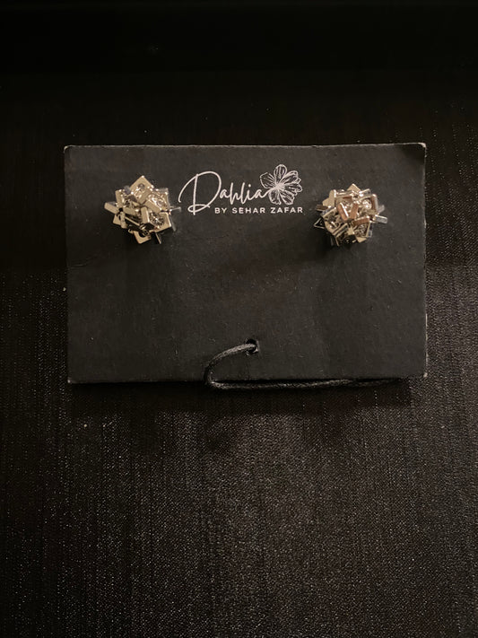 Gold geometric earrings with interlocking metallic pieces on black branded card