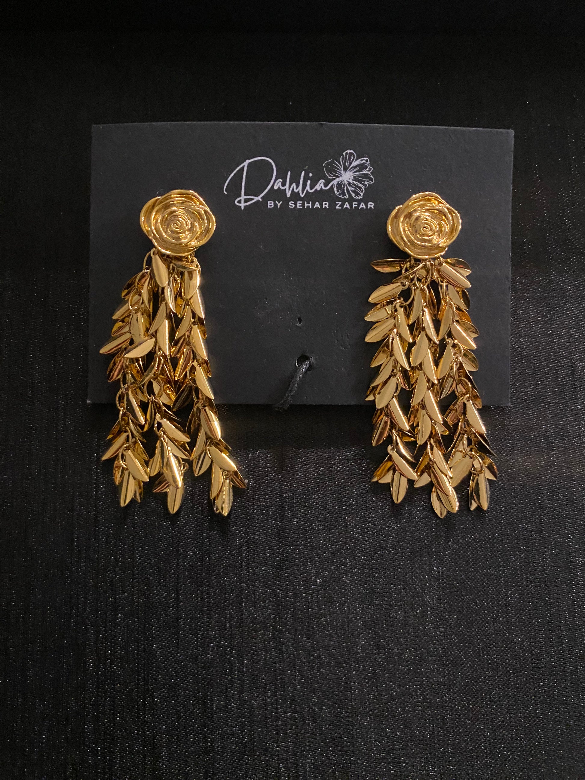 Gold rose chandelier earrings with cascading leaf drops on black branded card