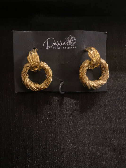 Gold twisted hoop earrings with rope texture on black branded card
