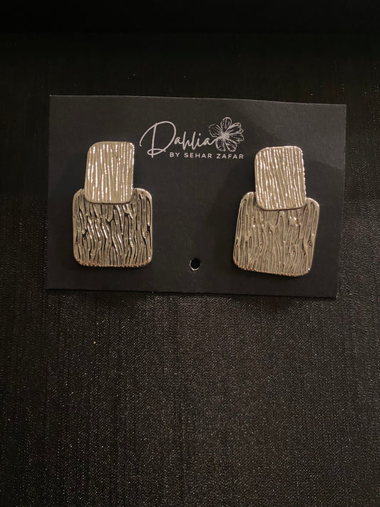 Gold rectangular earrings with vertical groove texture on black branded card