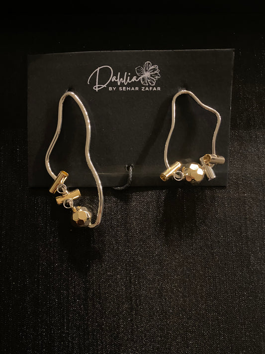 Asymmetrical silver earrings with wavy outline and mixed gold and silver beads on black branded card