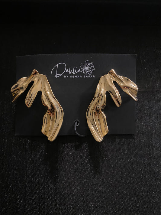 Gold abstract earrings with flowing leaf-like shape on black branded card