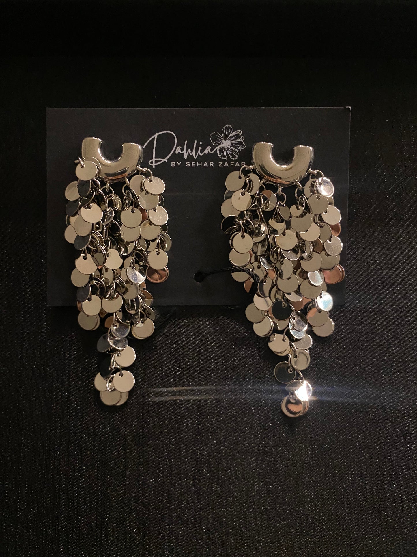 Gold cascading disc earrings with curved top accent on black branded card