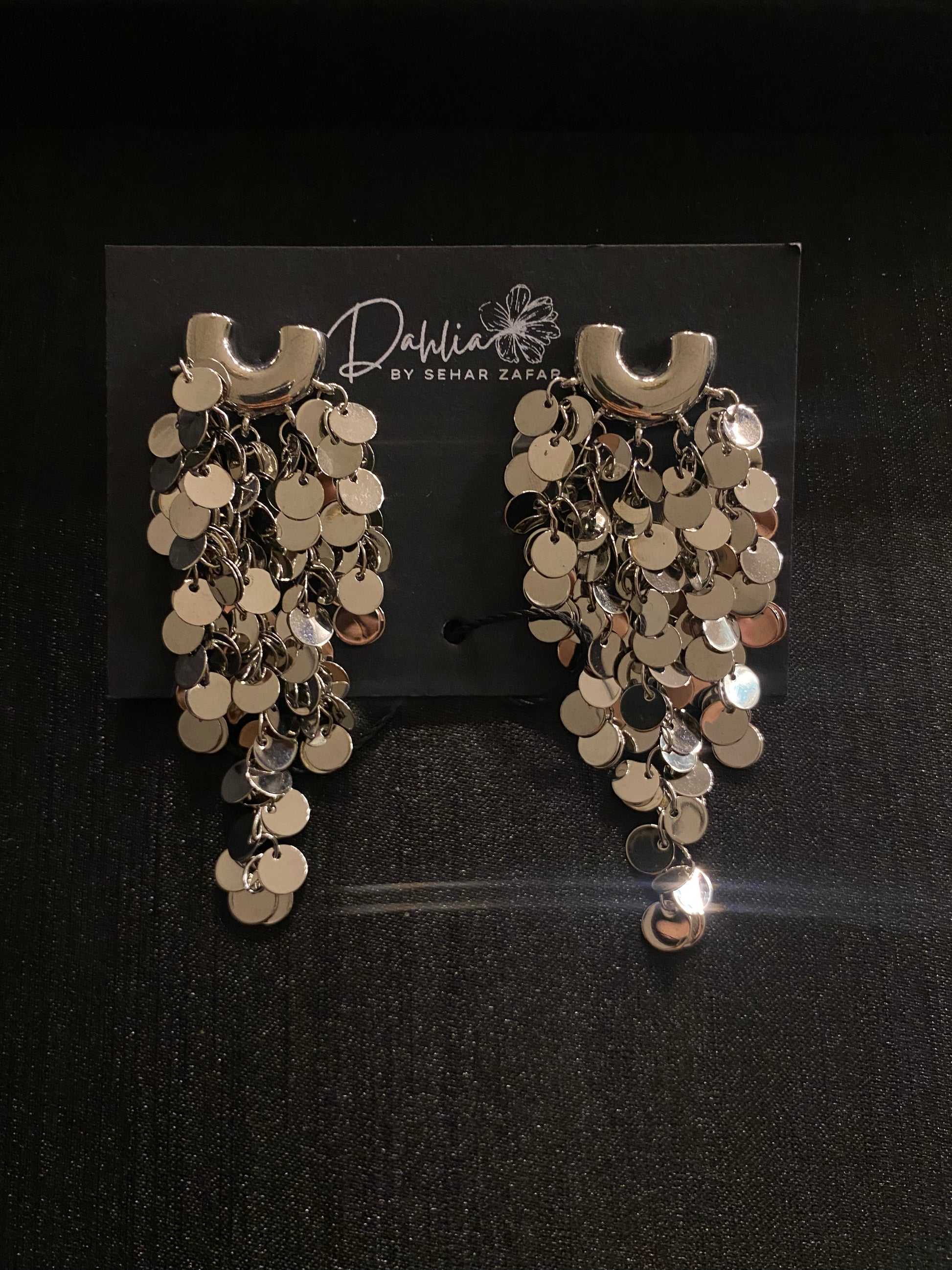 Gold cascading disc earrings with curved top accent on black branded card