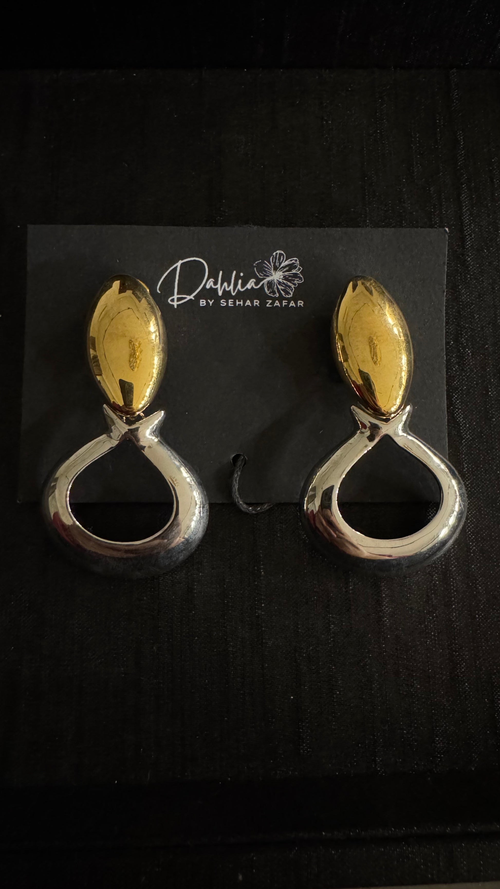 Gold and silver teardrop earrings with oval stud accent on black branded card