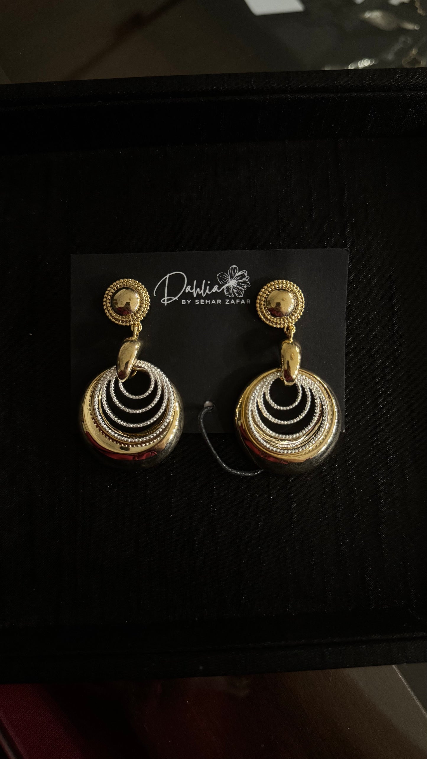 Gold and silver layered circle earrings with beaded stud on black branded card
