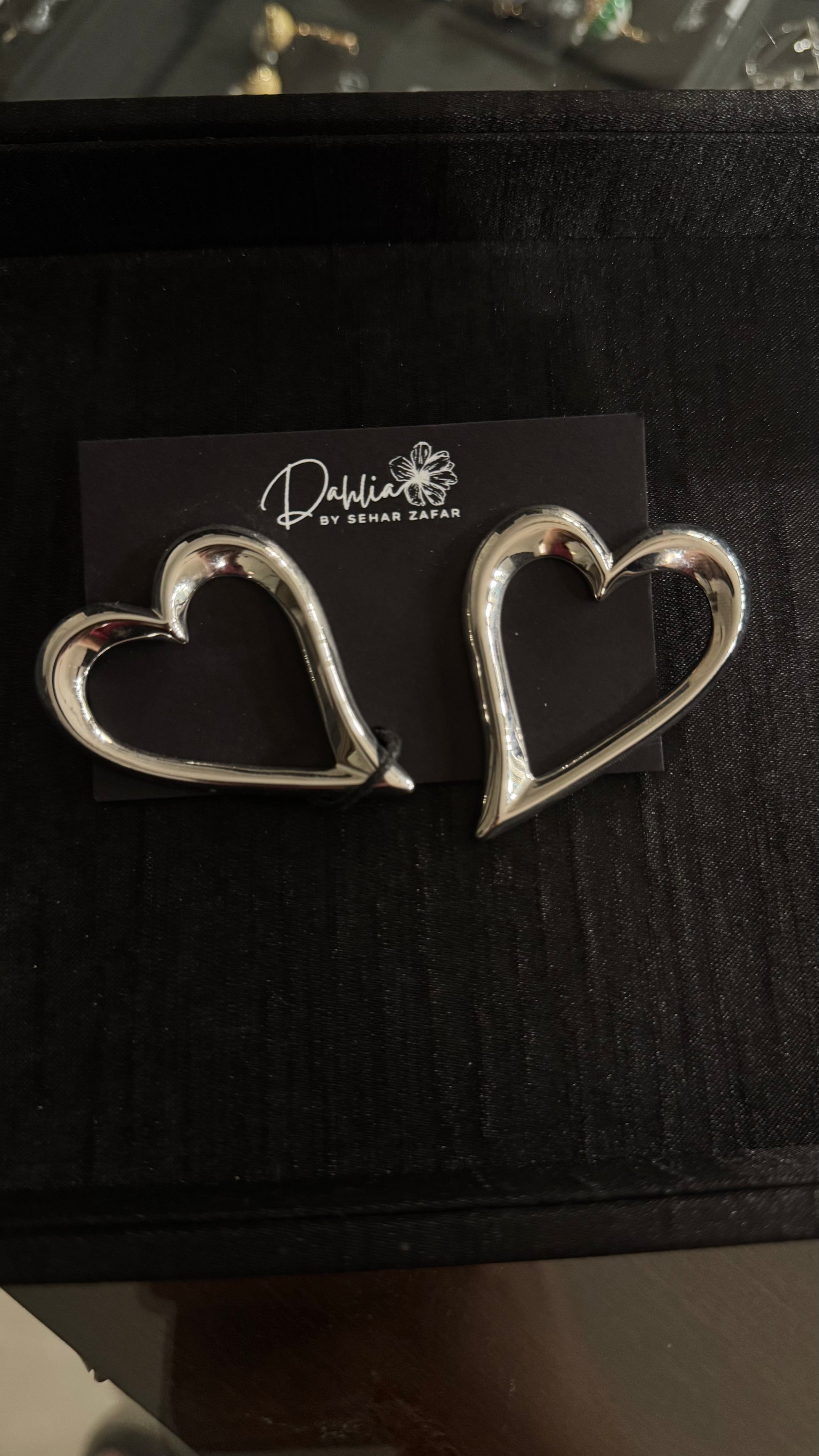 Gold heart-shaped accessories with sleek modern design on black branded card