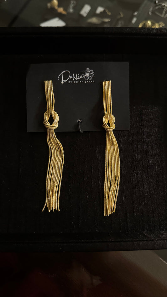 Gold tassel earrings with knotted top and flowing strands on black branded card