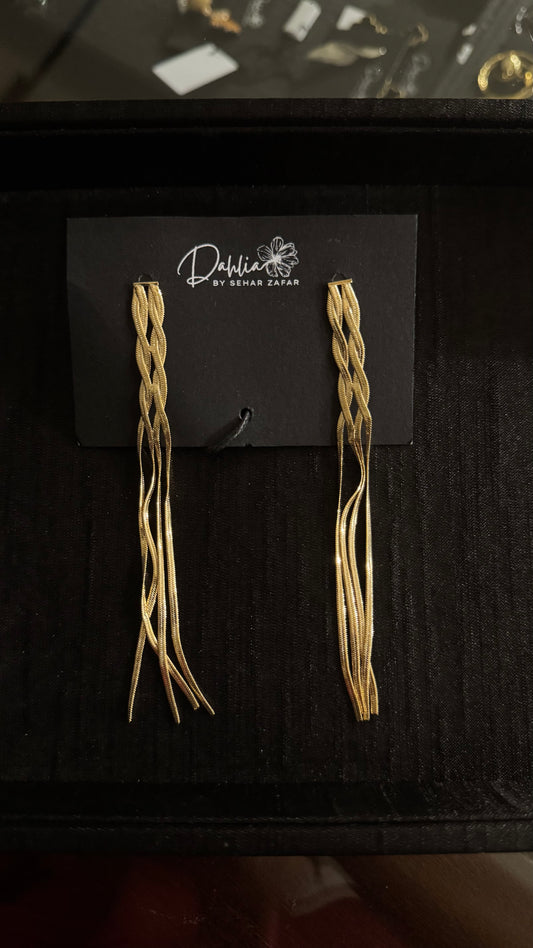 Gold braided dangle earrings with flowing metallic strands on black branded card