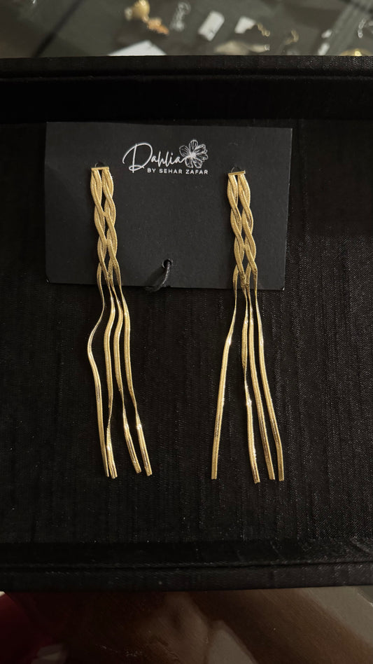 Gold braided strand earrings with wavy dangle design on black branded card