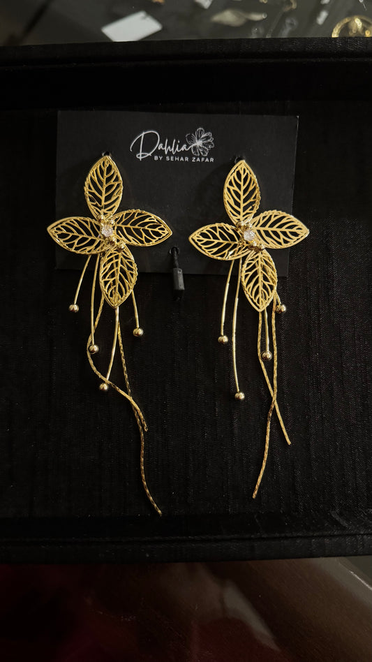 Gold filigree floral earrings with beaded tassel strands on black branded card