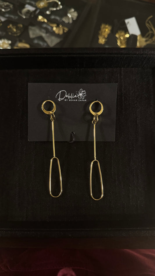 Gold minimalist oval loop earrings with vertical bar drop on black branded card